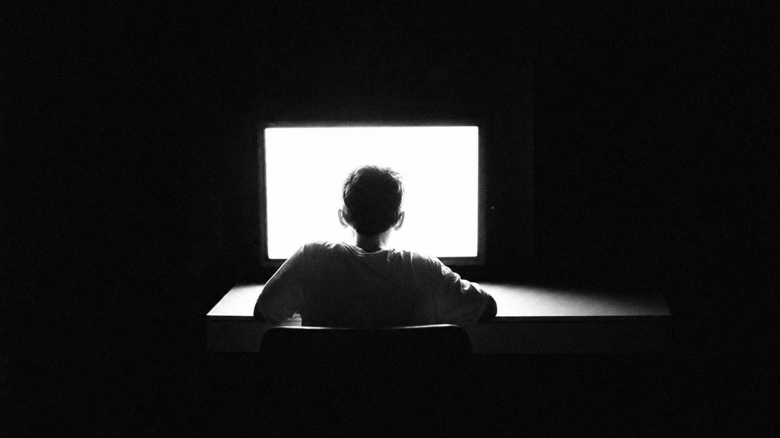 Someone working at a single bright monitor in a dark room