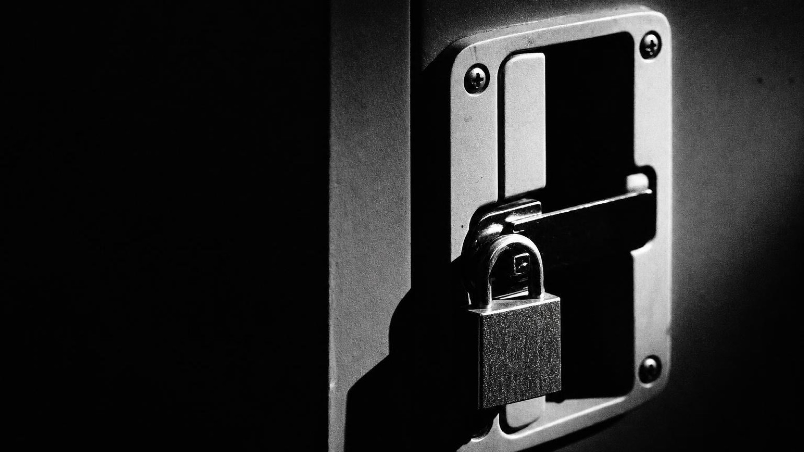 A padlock closed on a steel equipment cabinet