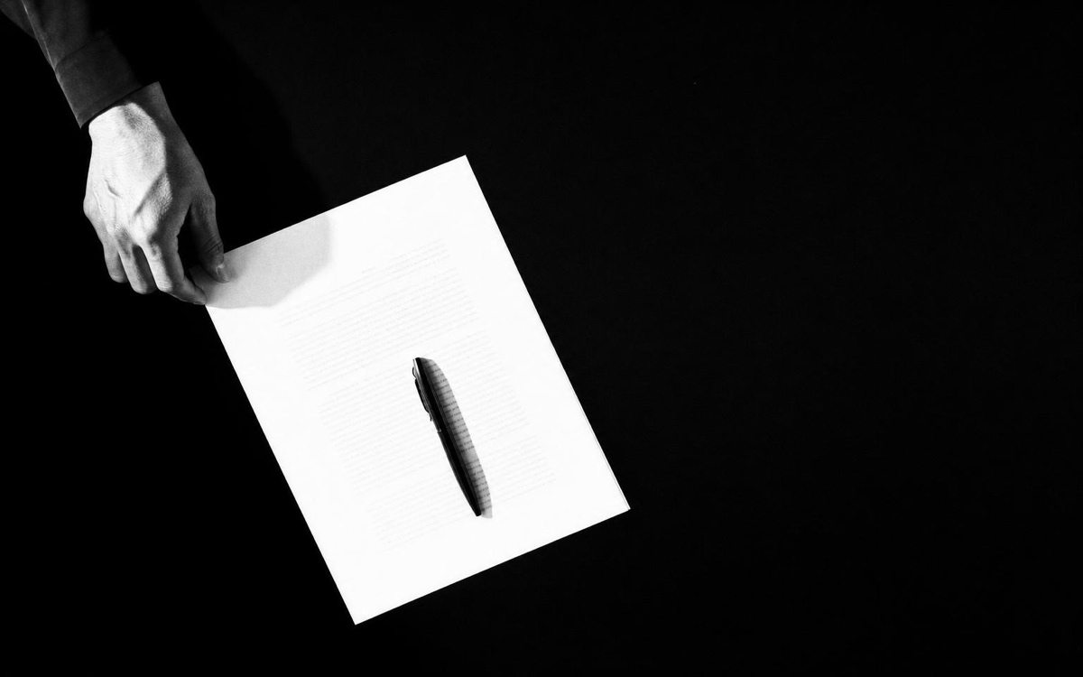 A hand holding a single marked sheet of paper